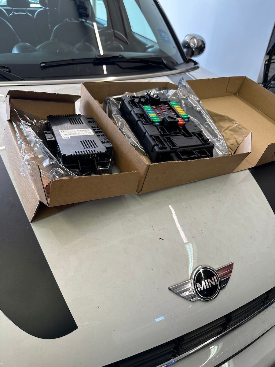 A white mini cooper with a box on the hood