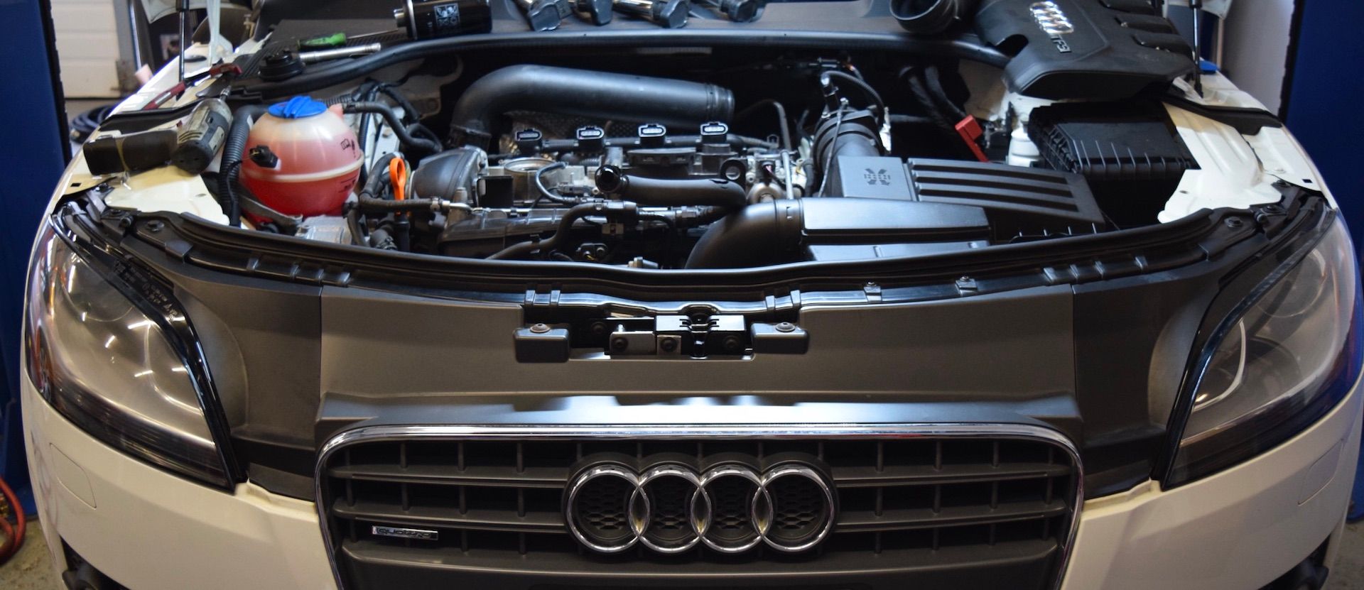 The hood of an audi is open and the engine is visible.