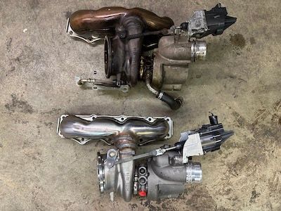 Two turbochargers are sitting next to each other on the ground.