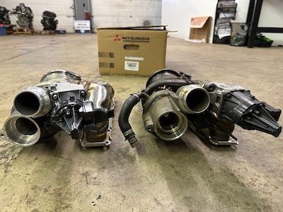 Two turbochargers are sitting next to each other in a garage.