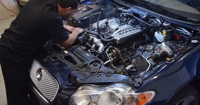 A man is working on the engine of a car.