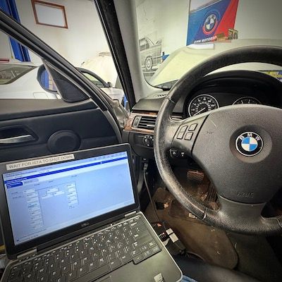 A laptop is sitting in the driver 's seat of a bmw.