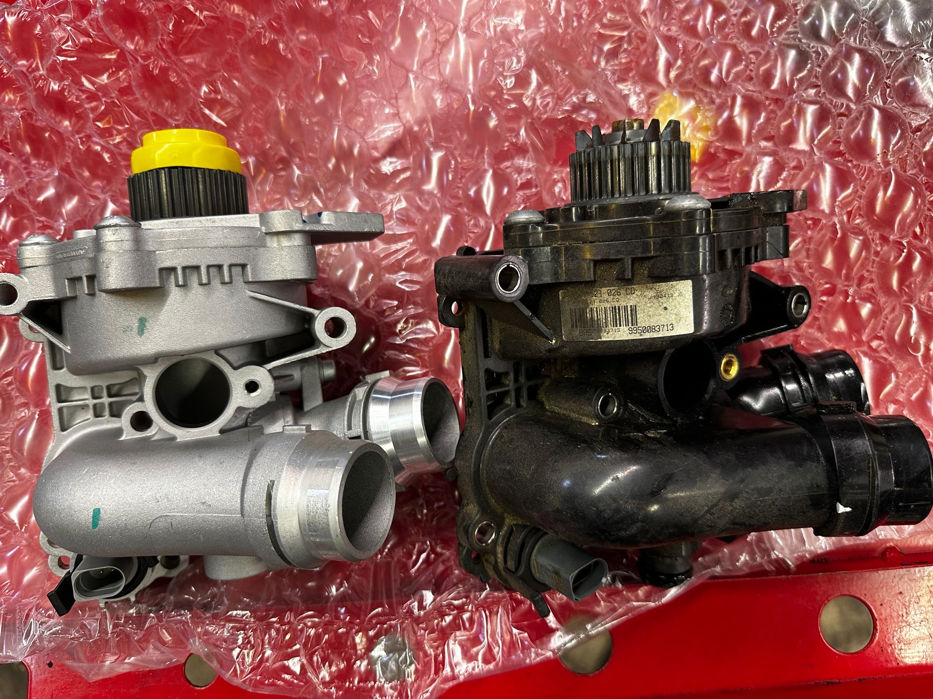 Two different types of engine parts are sitting on top of bubble wrap.