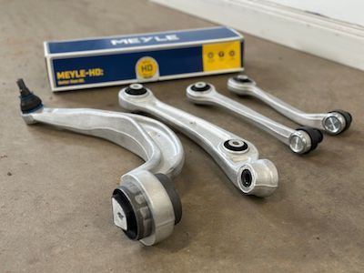 A set of suspension parts sitting on top of a concrete floor next to a box.