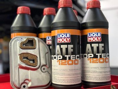 Four bottles of liqui moly atf top tec 1200 are sitting on a red table.