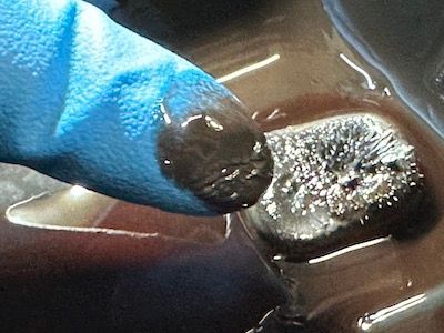 A person wearing a blue glove is holding a black object