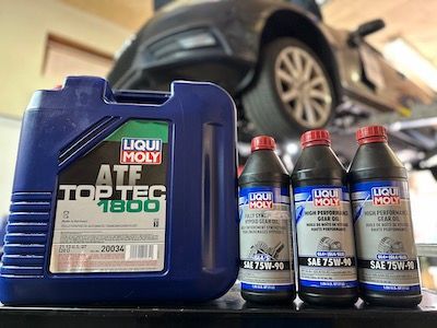 A bottle of liqui moly atf top tec 1800 is sitting on a table next to a car.