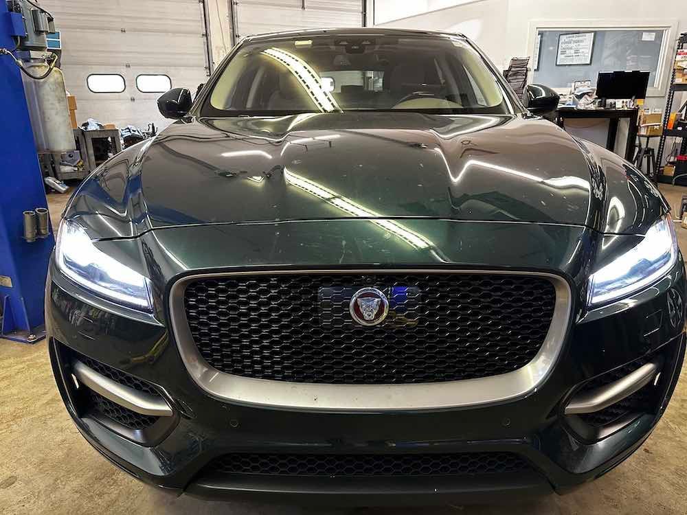 A black jaguar f pace is parked in a garage.