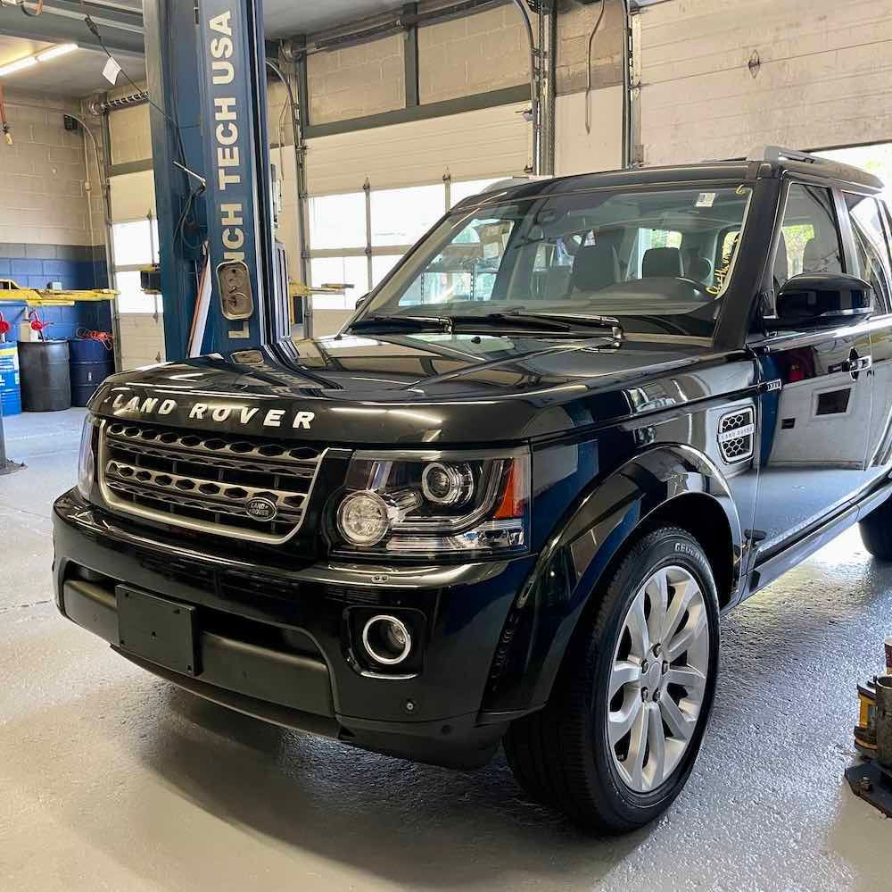 A black land rover is parked in a garage.