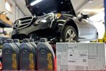 A mercedes benz is sitting on a lift in a garage next to bottles of oil.
