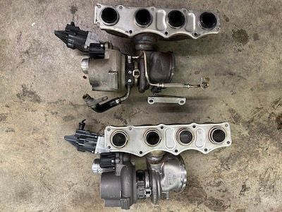 Two turbochargers are sitting next to each other on a concrete surface.