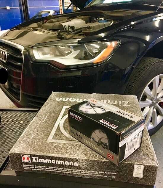 A black car is parked next to a box of brake pads.