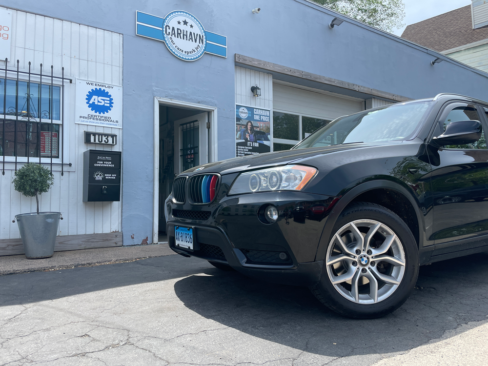 A black bmw x3 is parked in front of a car dealership.
