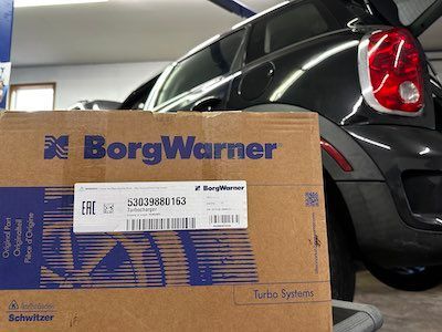 A box from borgwarner is sitting in front of a car