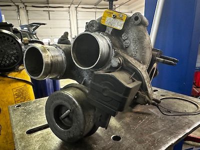 A turbocharger is sitting on top of a metal table in a garage.