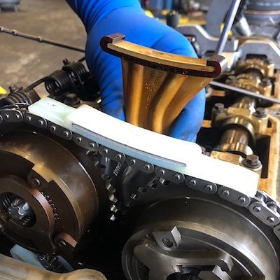 A person wearing blue gloves is working on a car engine