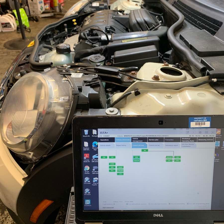 A dell laptop is sitting under the hood of a car