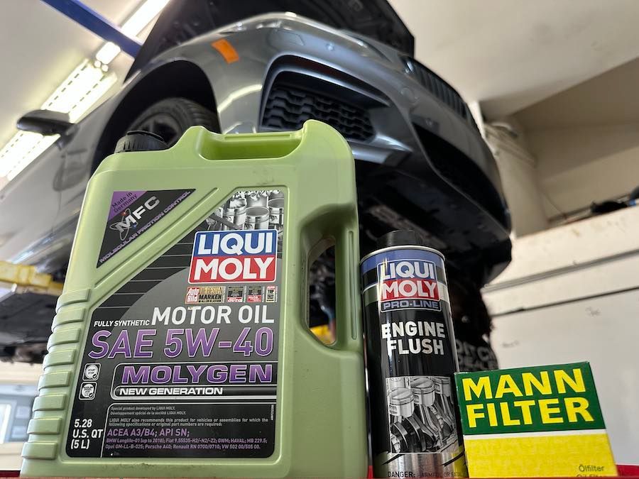 A bottle of liqui moly motor oil is sitting next to a car.