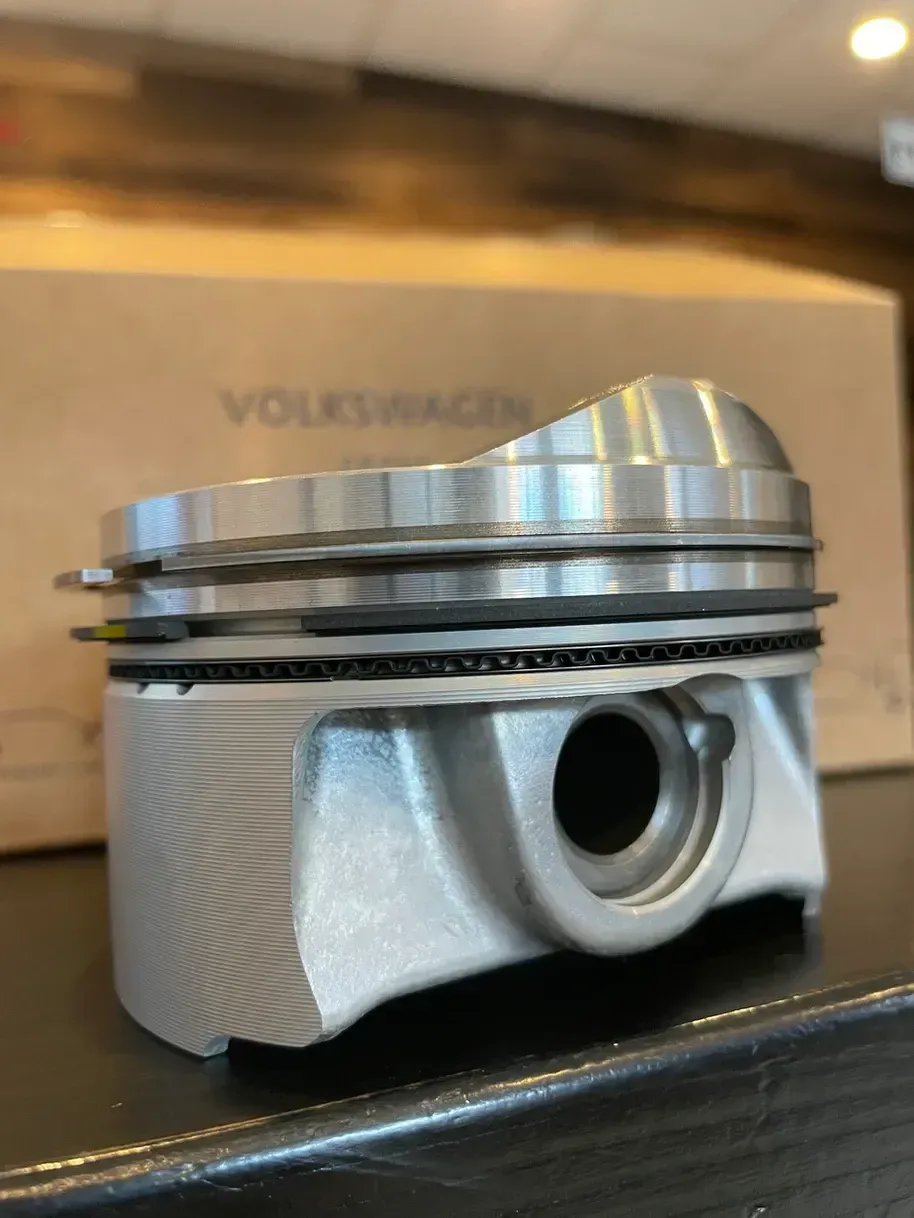 A piston is sitting on a table in front of a volkswagen box