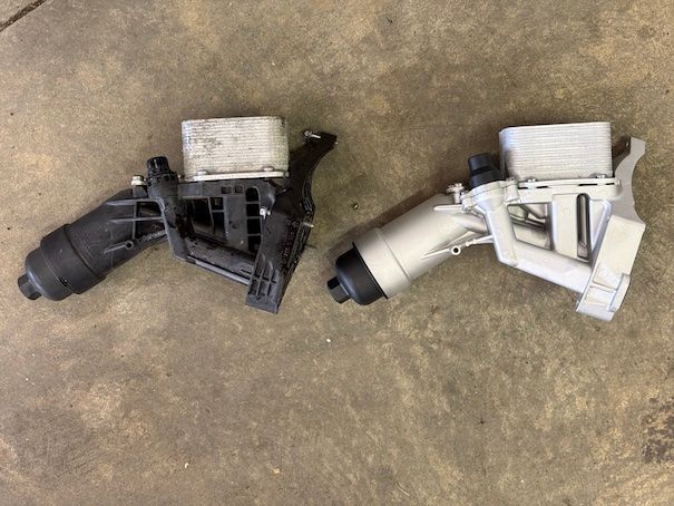 Two oil filter housings are sitting next to each other on the ground.