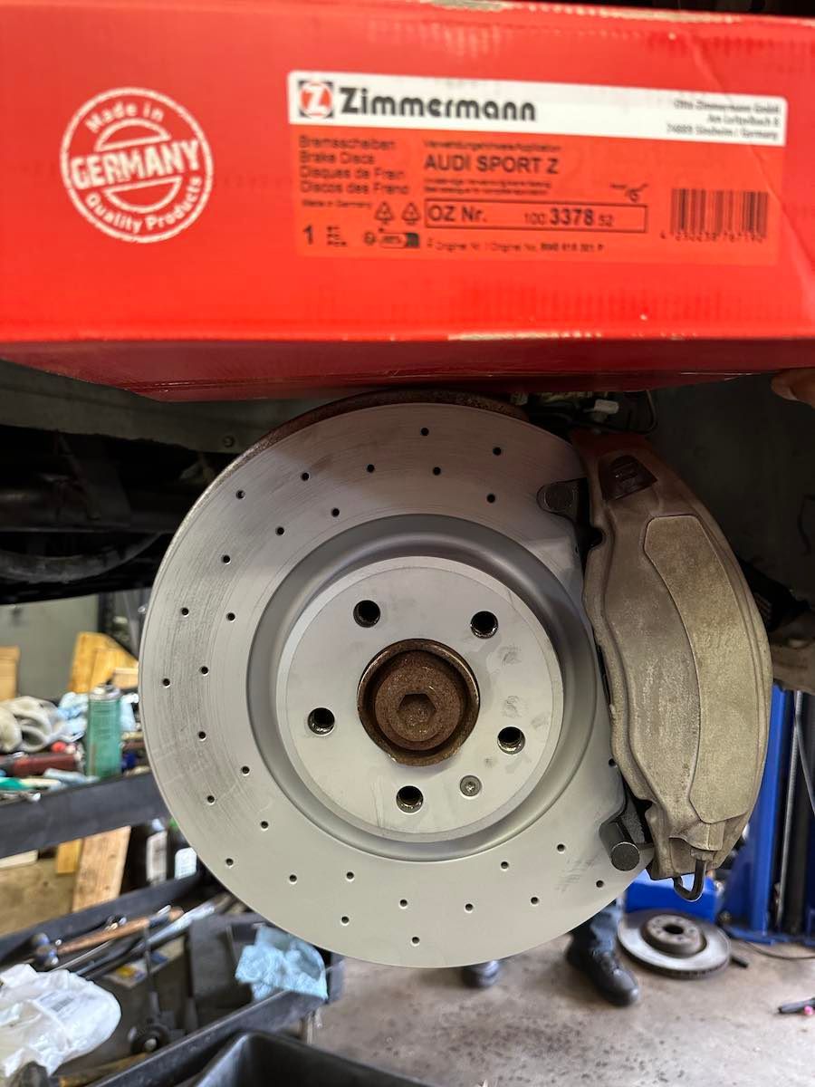 A brake disc is sitting on top of a box that says made in germany