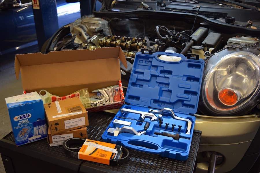 A car with the hood open is sitting on a table with tools on it.