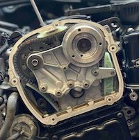 A close up of a car engine with a screwdriver in it.