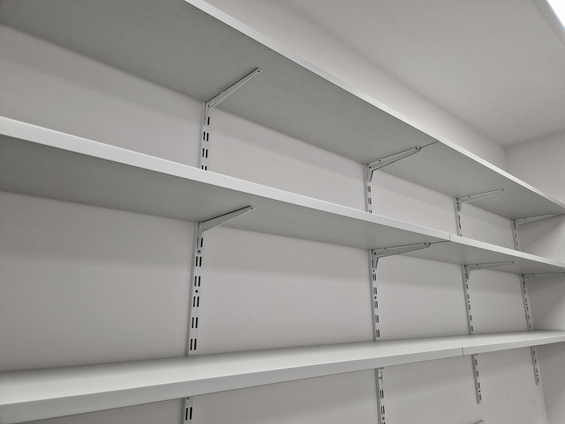 A row of empty shelves against a white wall