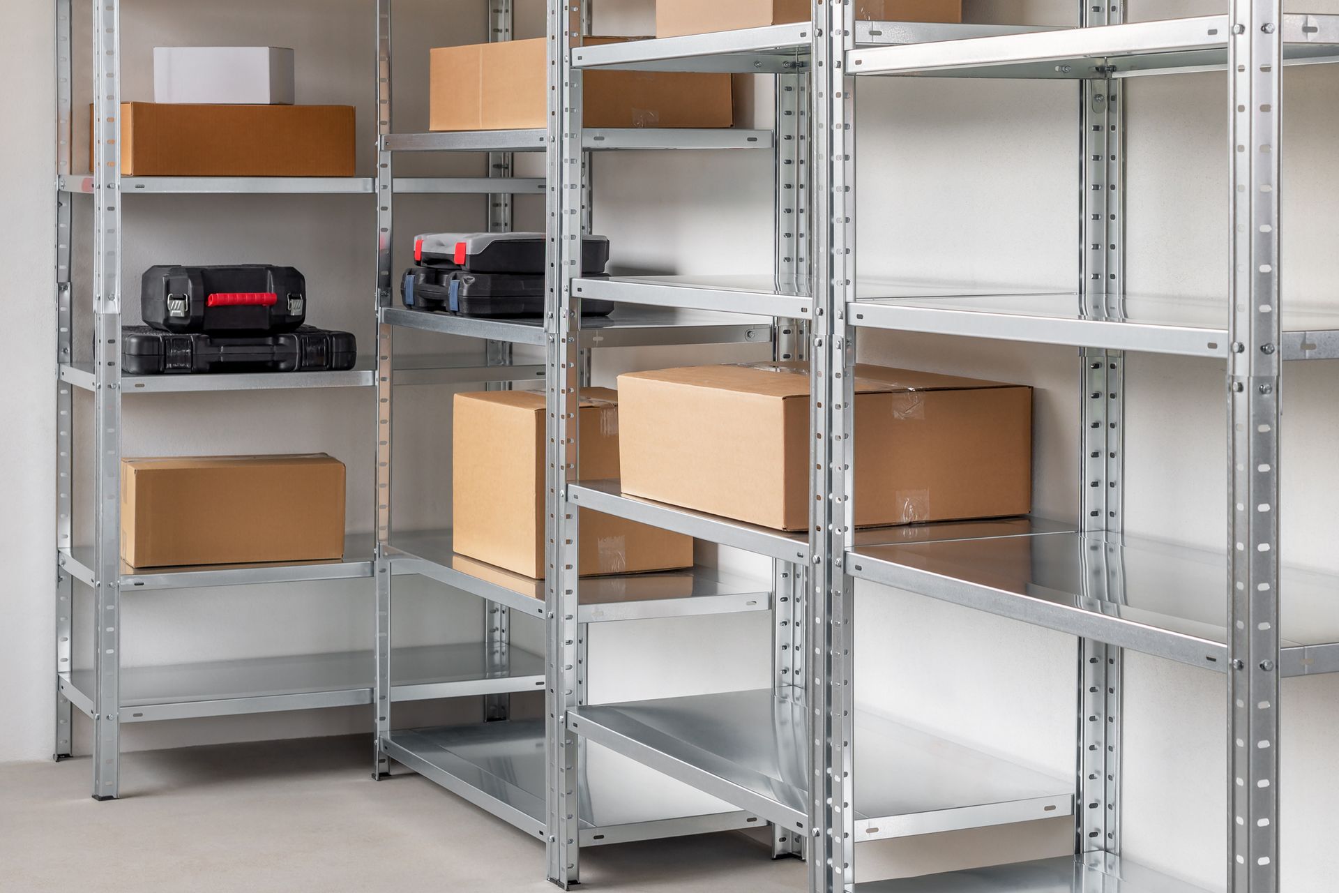 Metal shelving units filled with boxes and some electronics in a storage room.