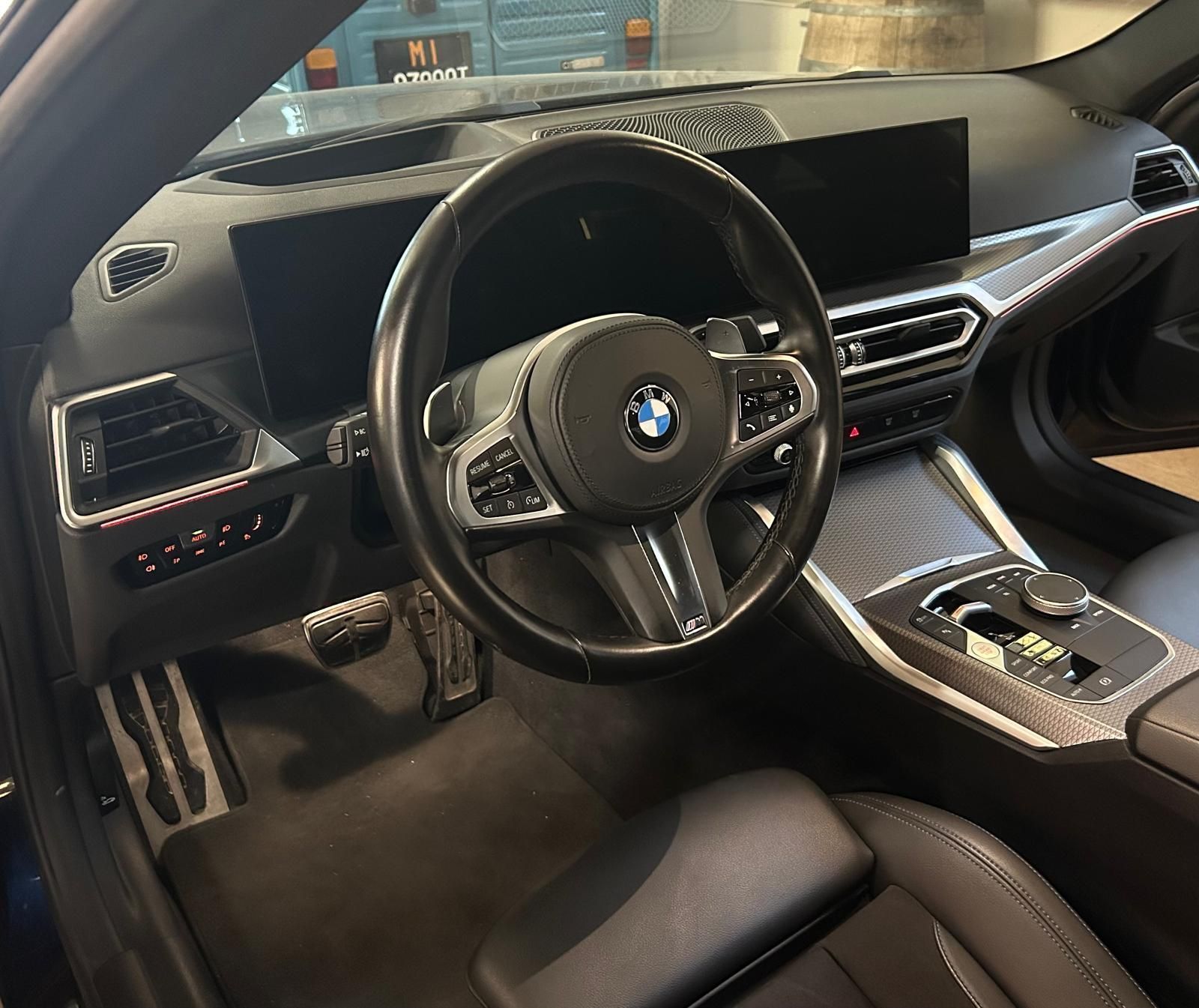 Interni di una BMW, con volante in pelle, cruscotto, display digitale e console centrale.