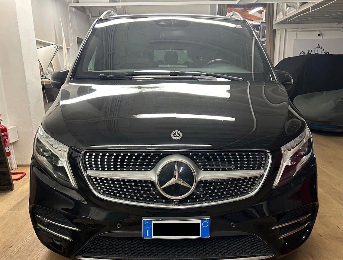 Vista frontale di un furgone di lusso Mercedes-Benz Classe V nero parcheggiato al coperto.