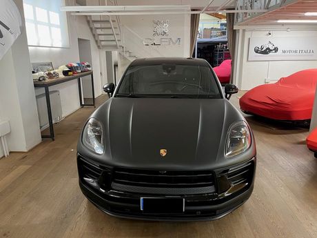 Un SUV Range Rover color argento parcheggiato all'interno di uno showroom, con sullo sfondo auto coperte da teli rossi.