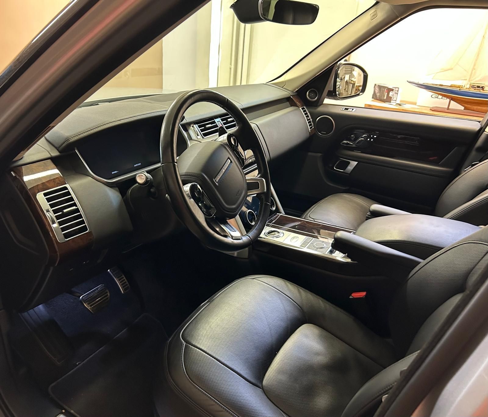 Vista laterale ravvicinata degli interni di un SUV di lusso, con sedili avvolgenti in pelle nera e console in legno lucido.