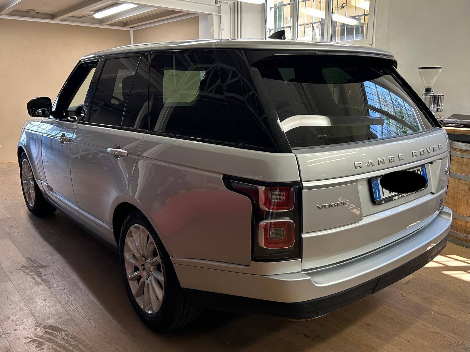 Un SUV Range Rover color argento parcheggiato in un garage coperto, visto da un'angolazione di tre quarti posteriore.