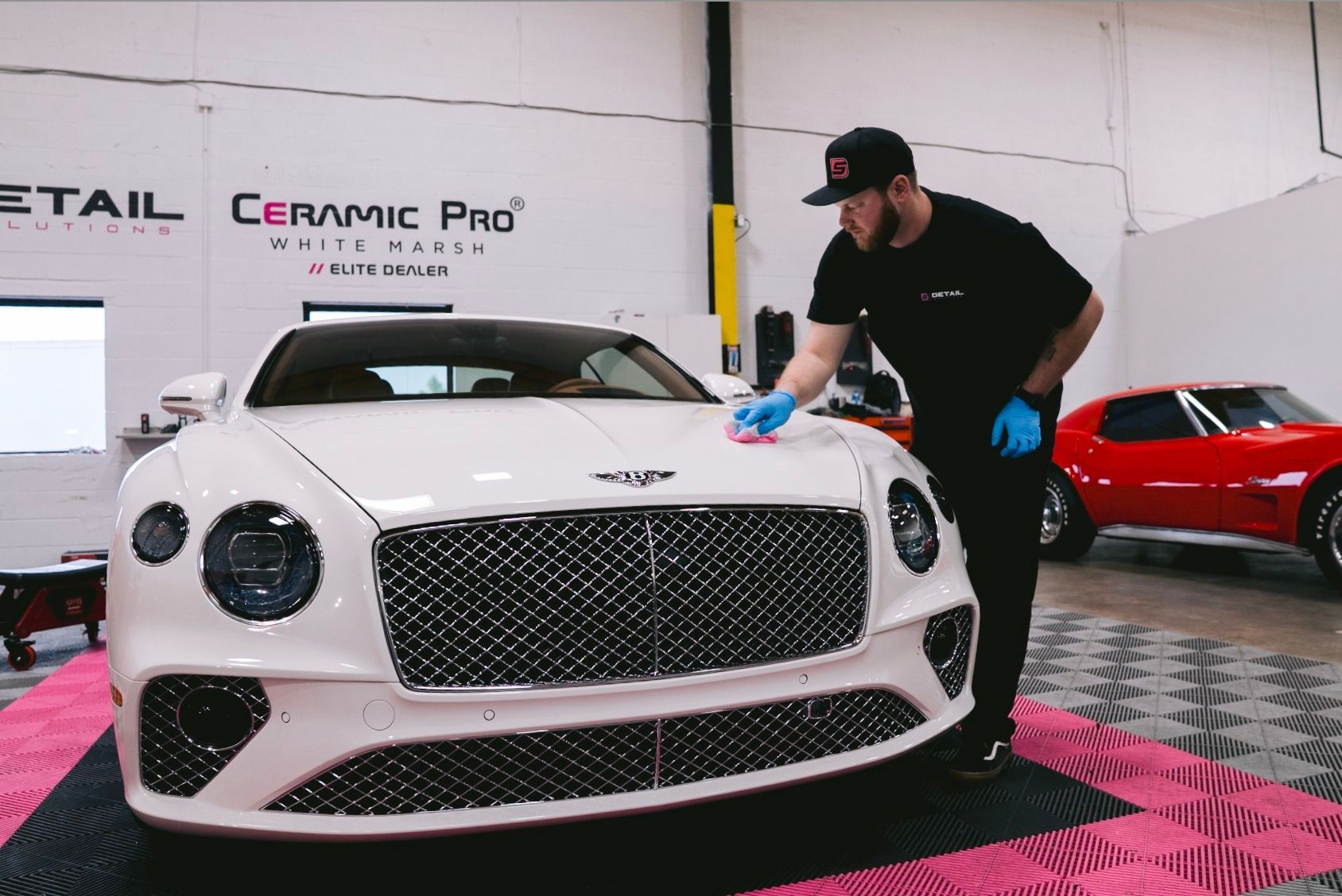 White luxury sports car being detailed by a worker in a garage showroom