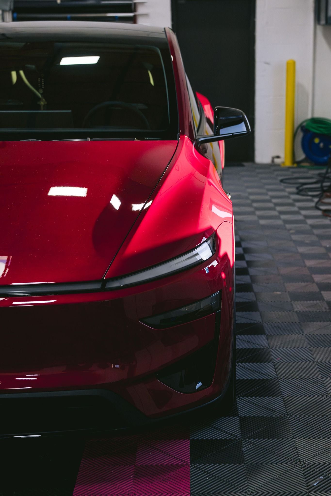Red Tesla with ceramic coating inside detailing shop showcasing deep gloss and paint protection