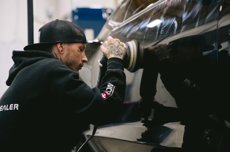a man is polishing a black car in a garage .