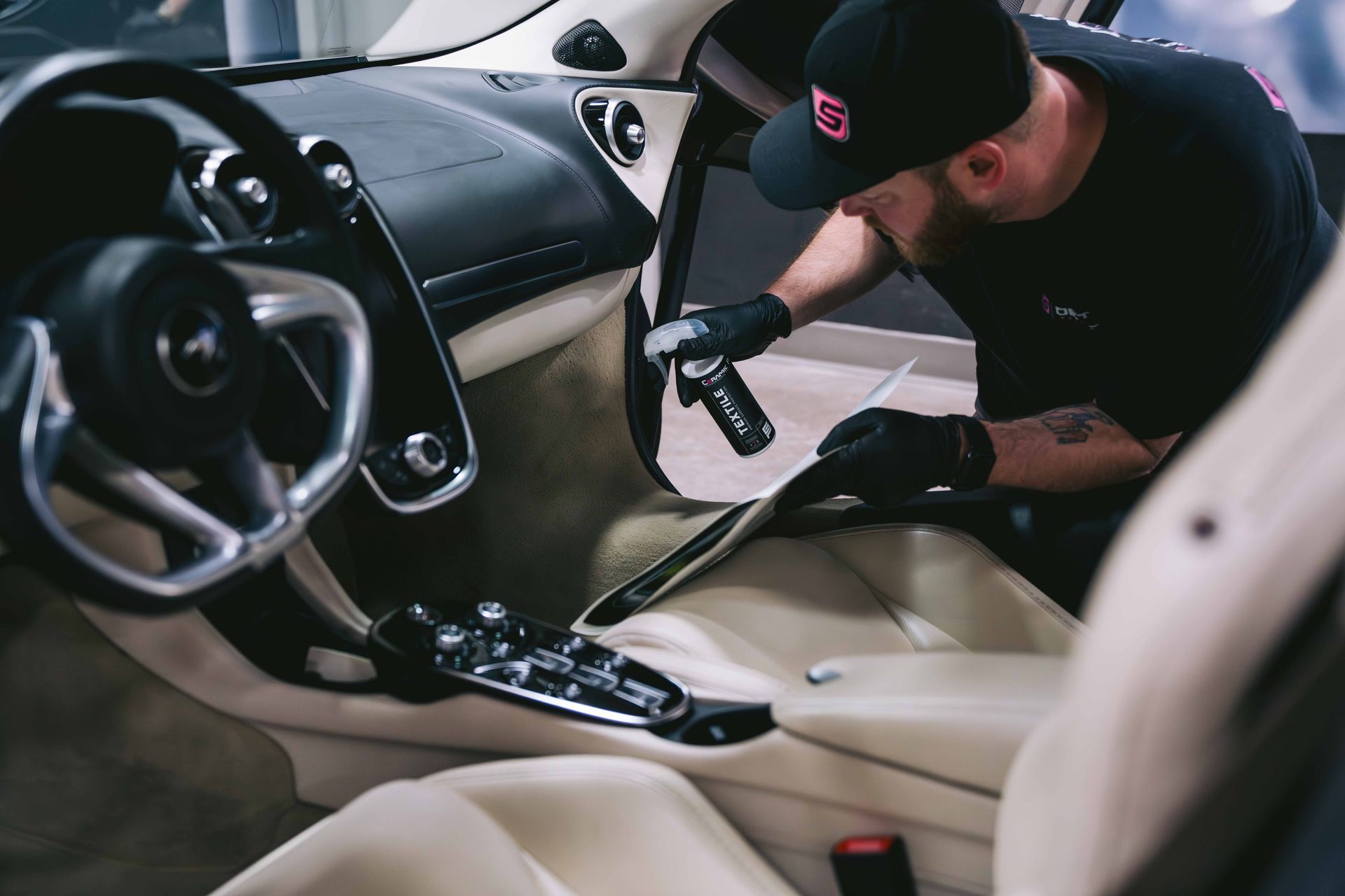 A man is cleaning the interior of a car with a vacuum cleaner.