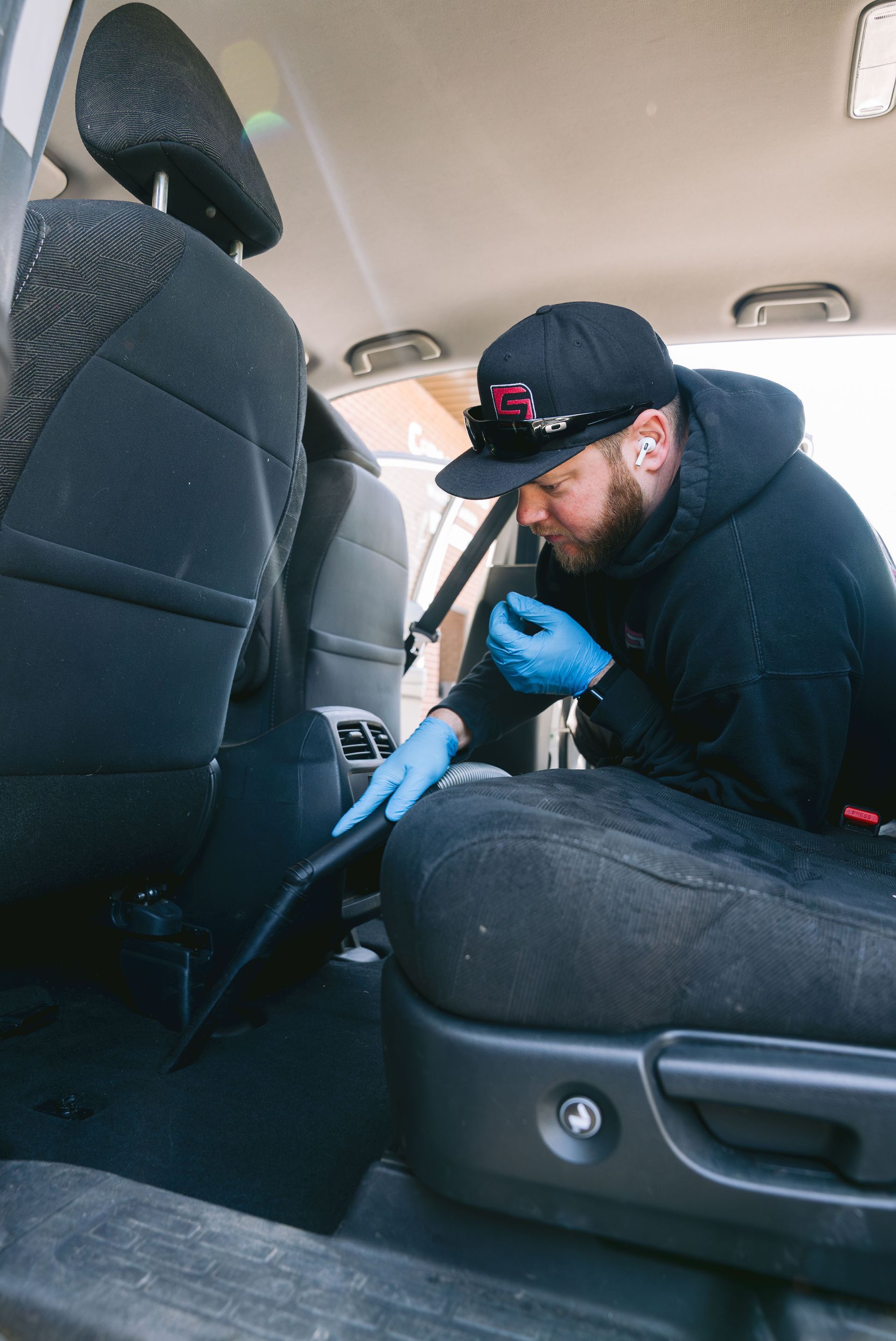 A man is cleaning the back seat of a car.