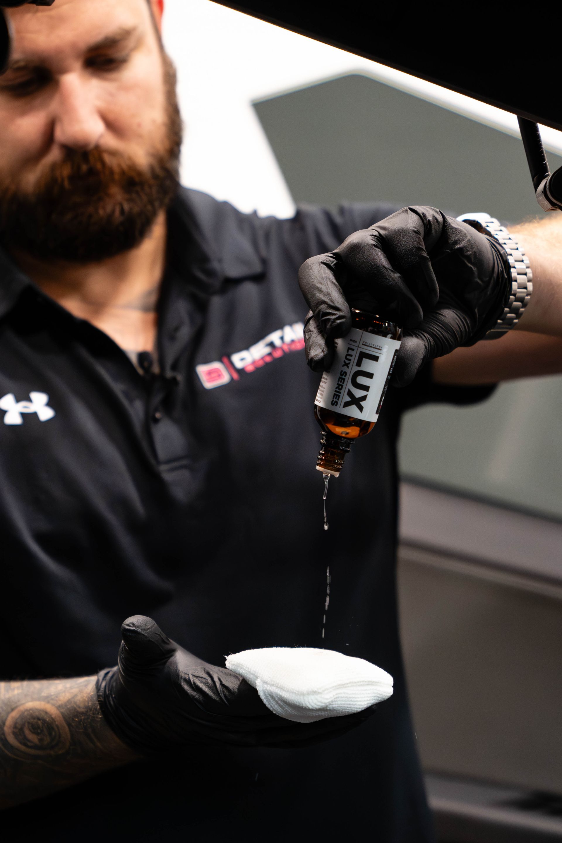 A man wearing black gloves is pouring a liquid into a cloth.