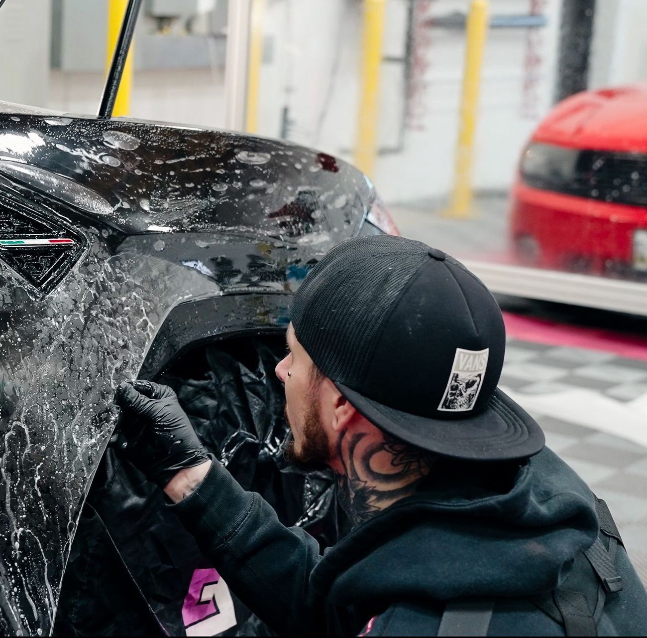 A man wearing a black hat is working on a car