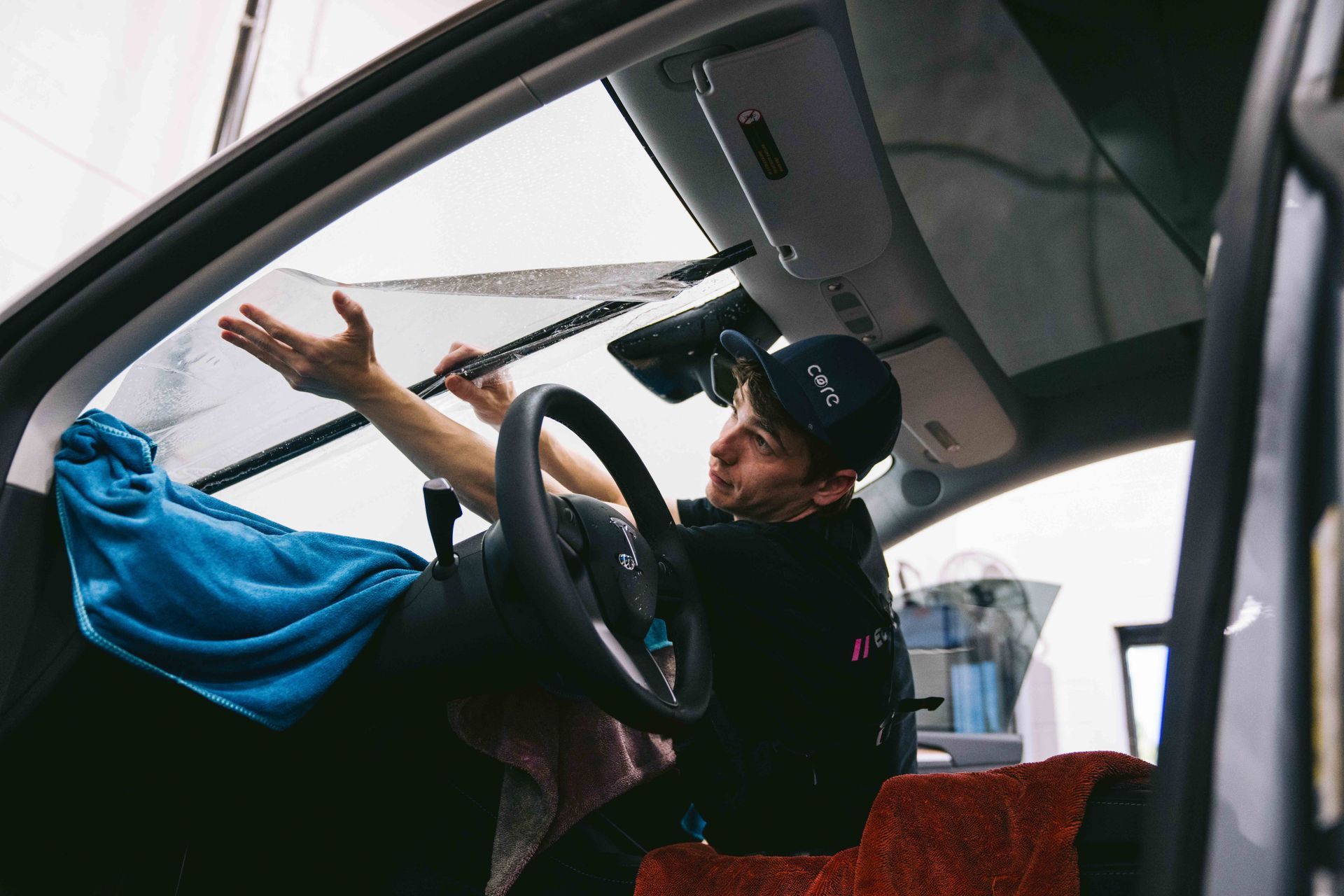 A man is cleaning the windshield of a car.