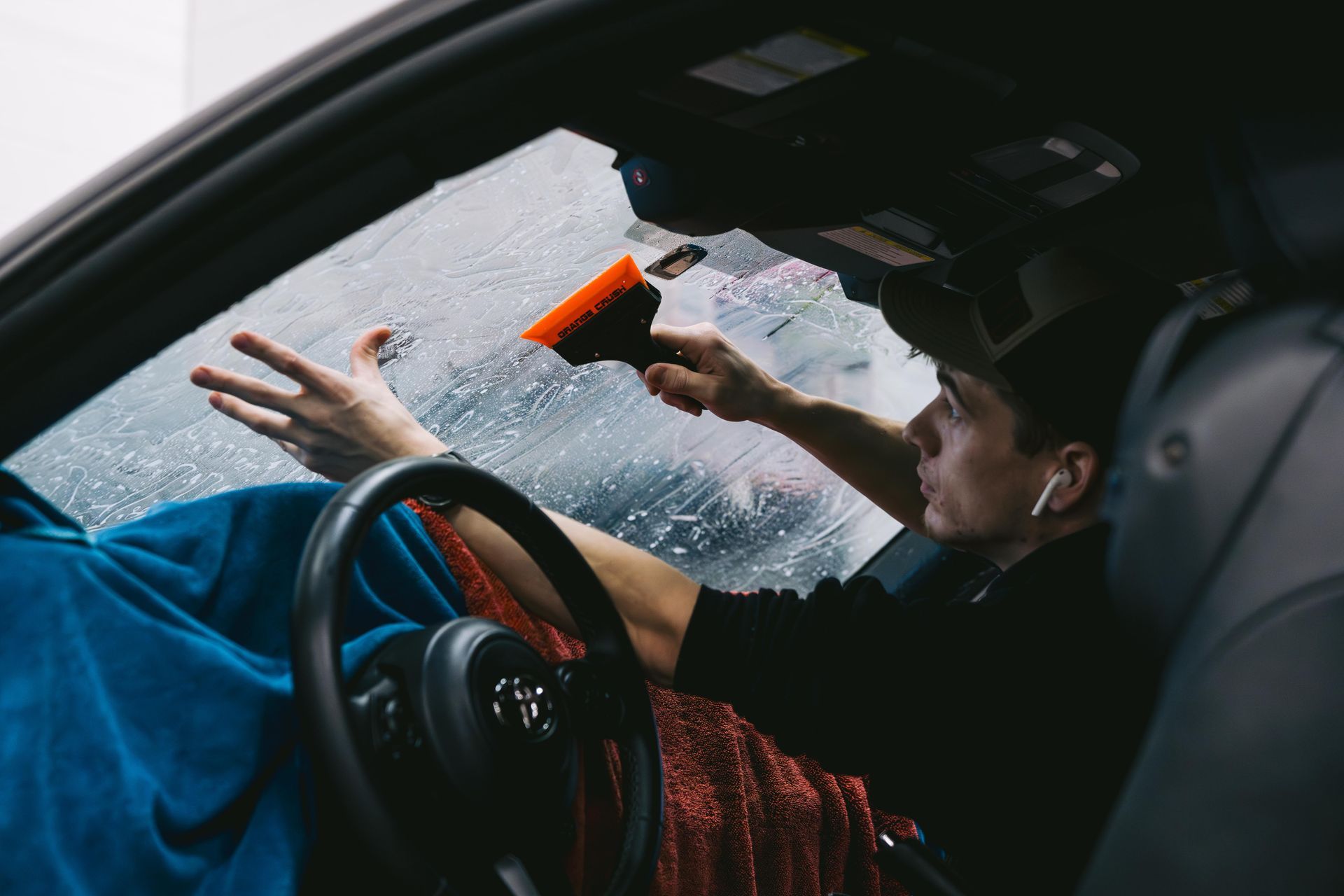 A person is applying tinted glass to a car windshield.