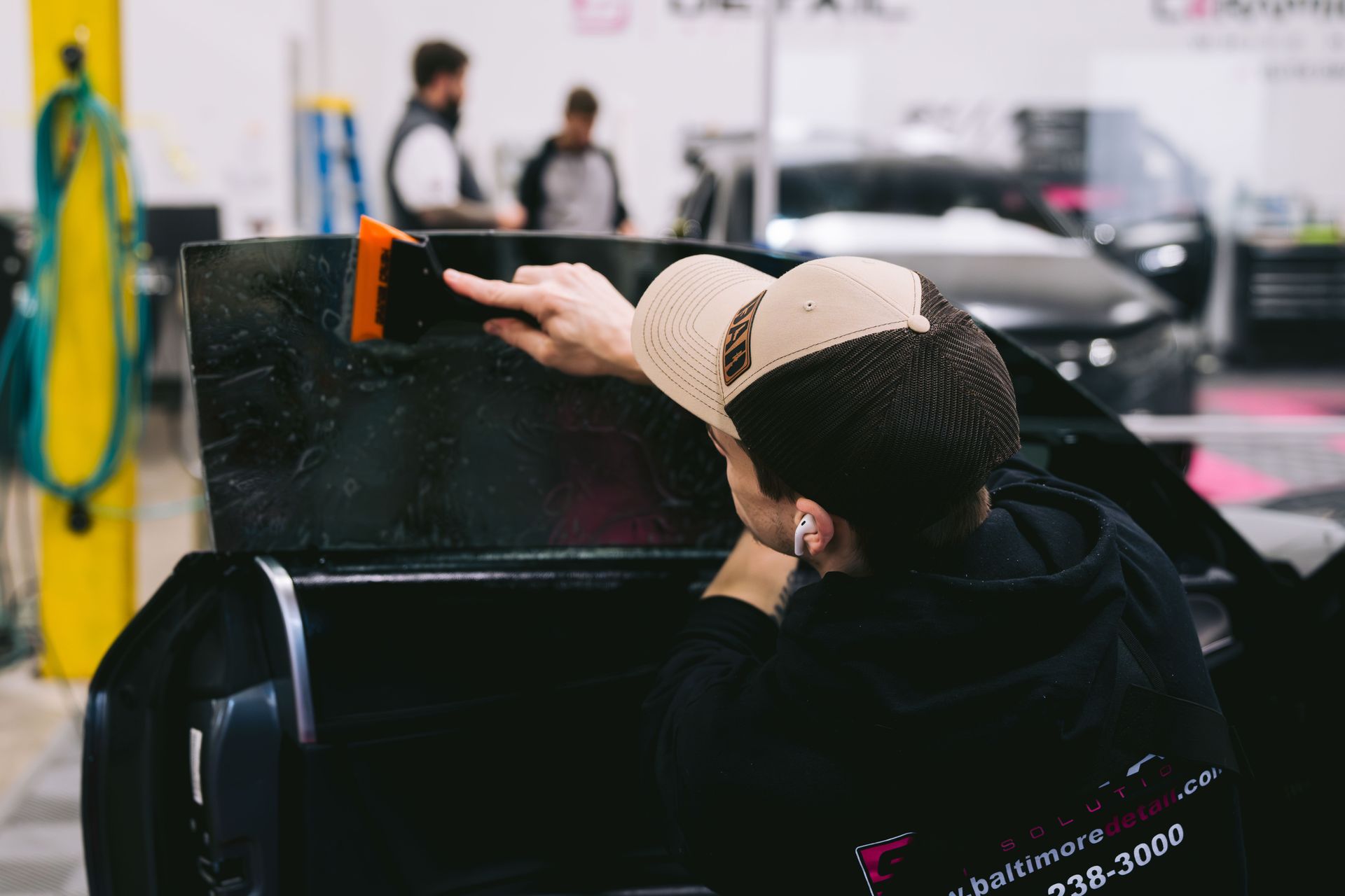 A man is applying window tinting to a car window.