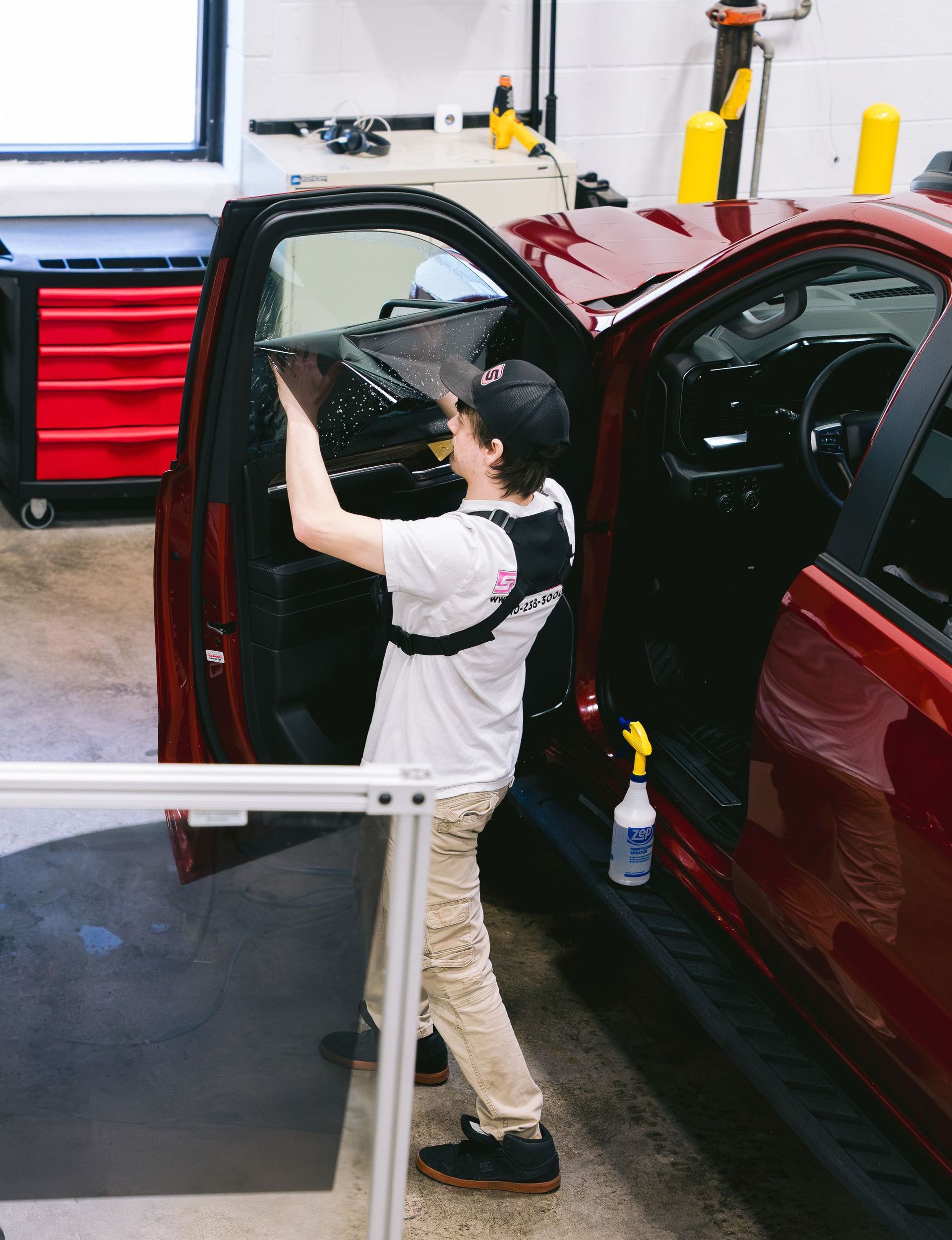 A person wearing black gloves is polishing a black car