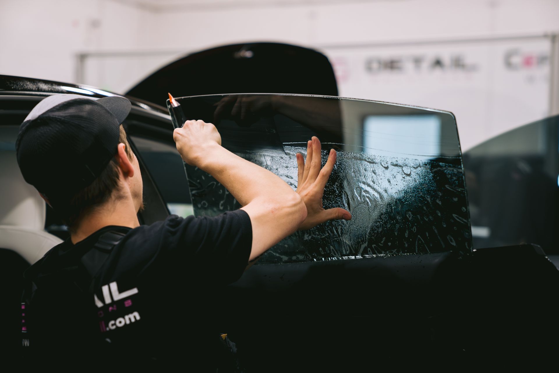 A man is applying window tinting to a car window.