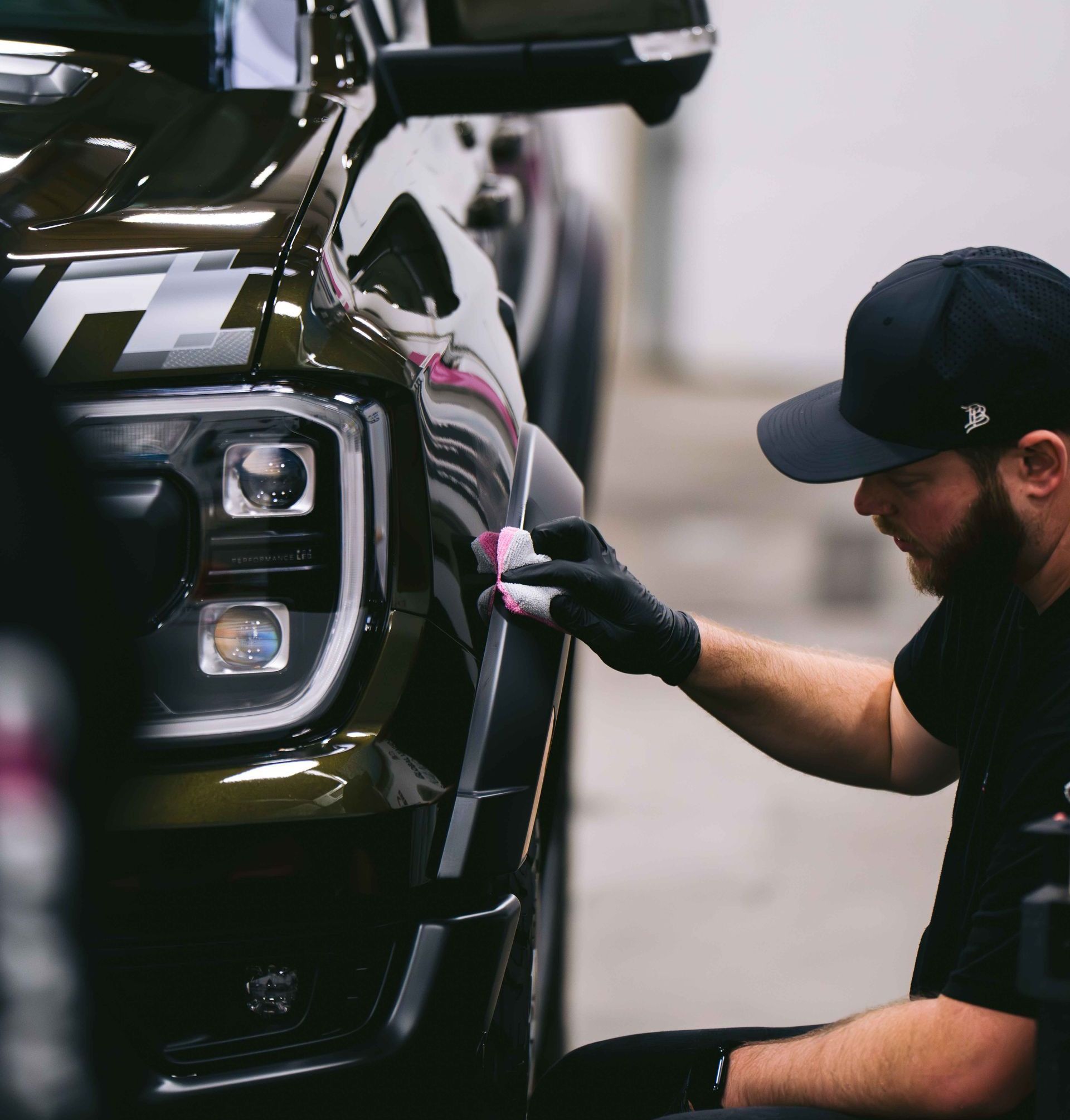 A man wearing a hat and gloves is polishing a car