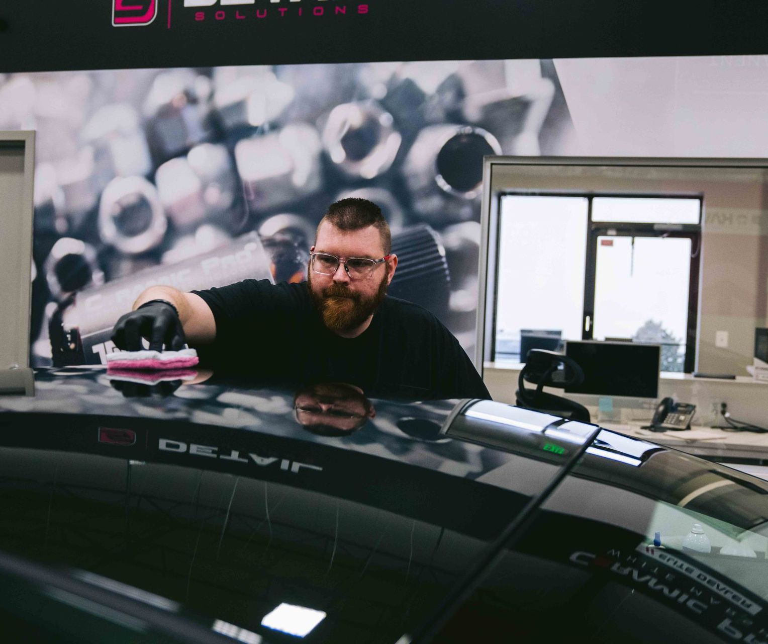 A man is polishing the hood of a black car