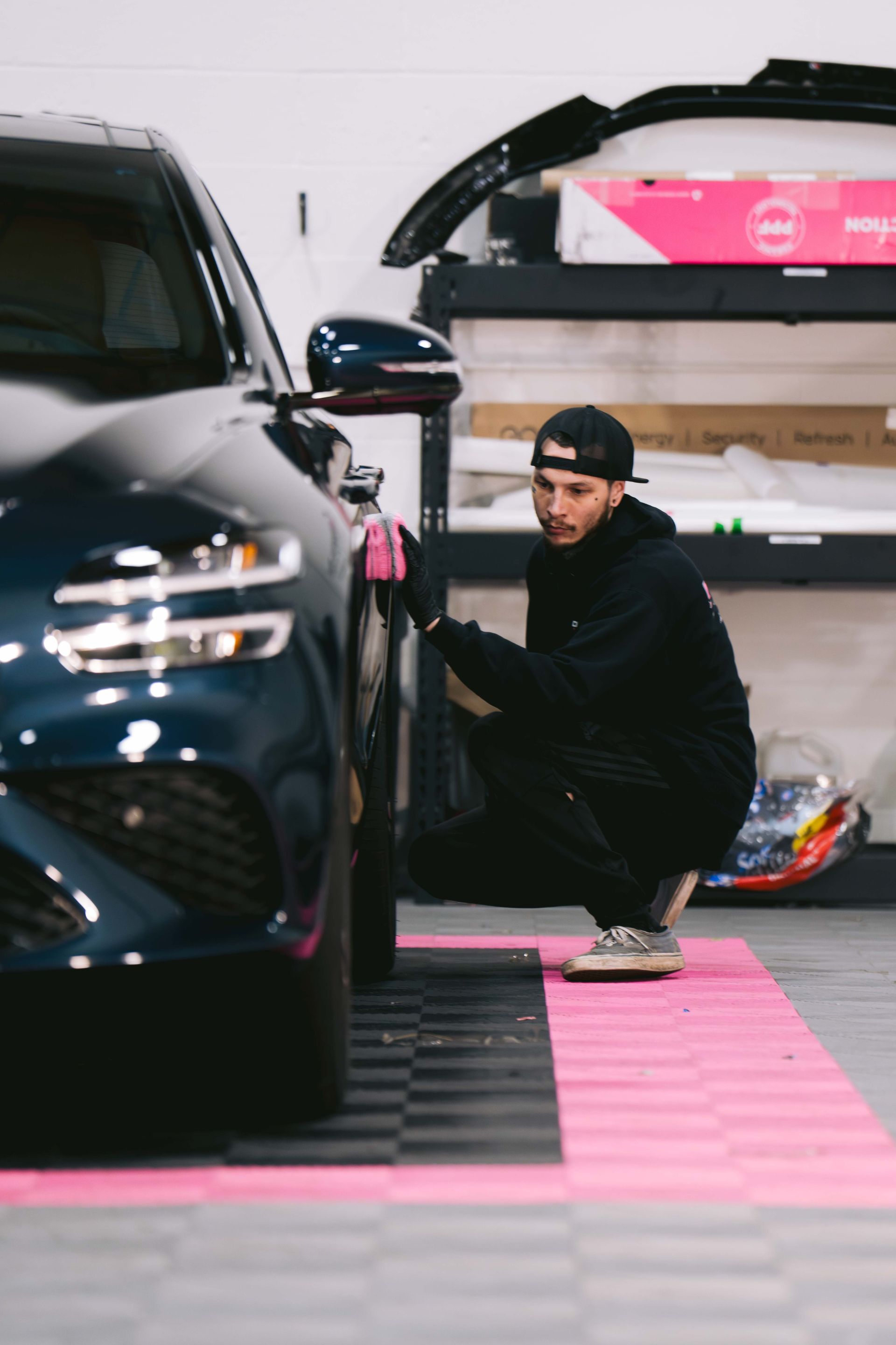 A person is polishing the hood of a blue car.