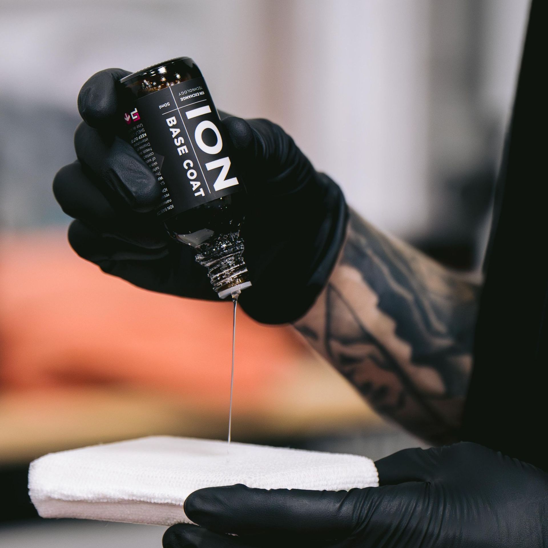 A person wearing black gloves is polishing the hood of a red car.